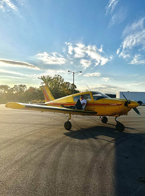 Student setting on wing of plane